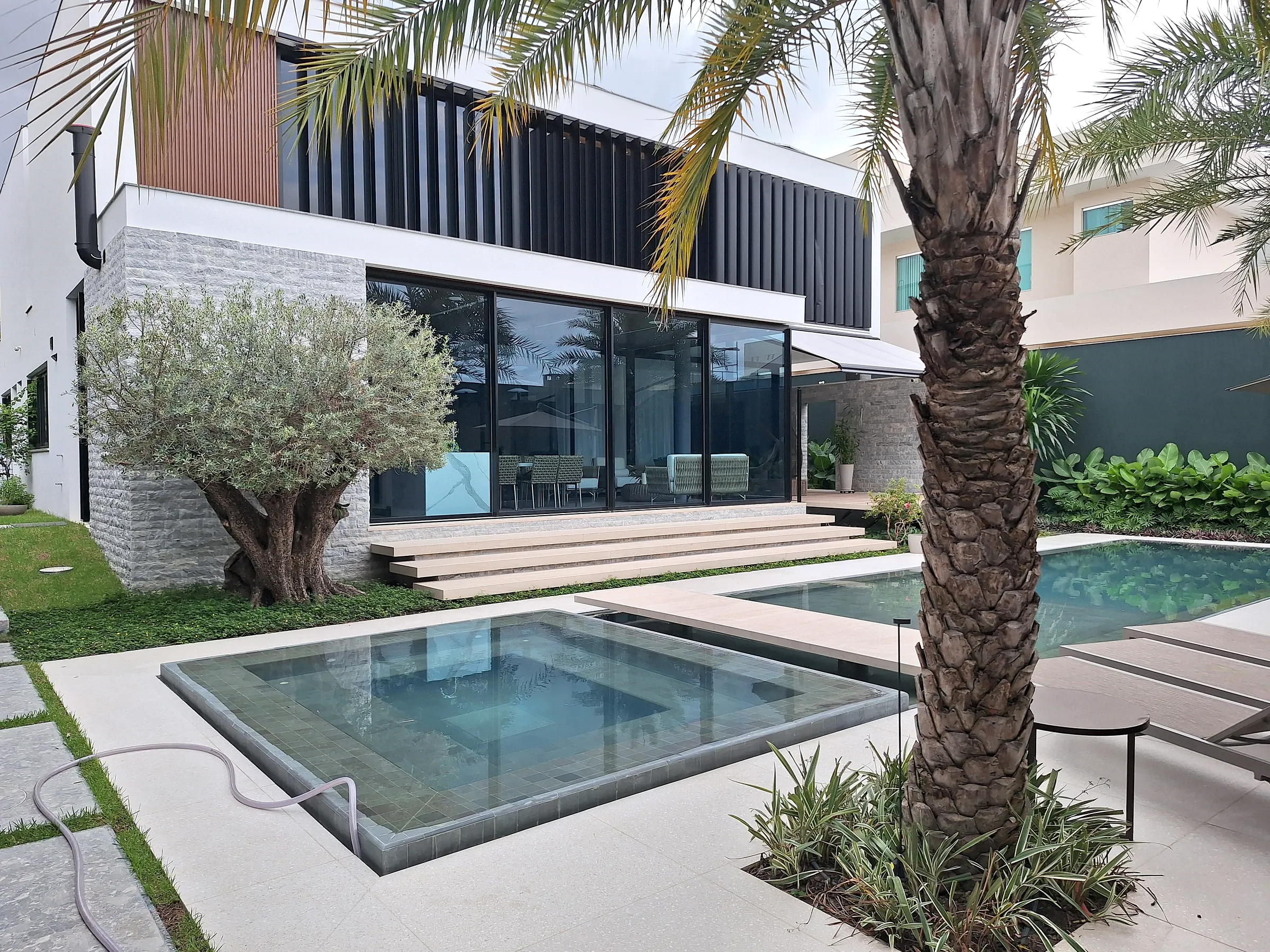Hoje: residência de alto padrão construída pela empresa, com oliveira, spa, piscina e palmeira.