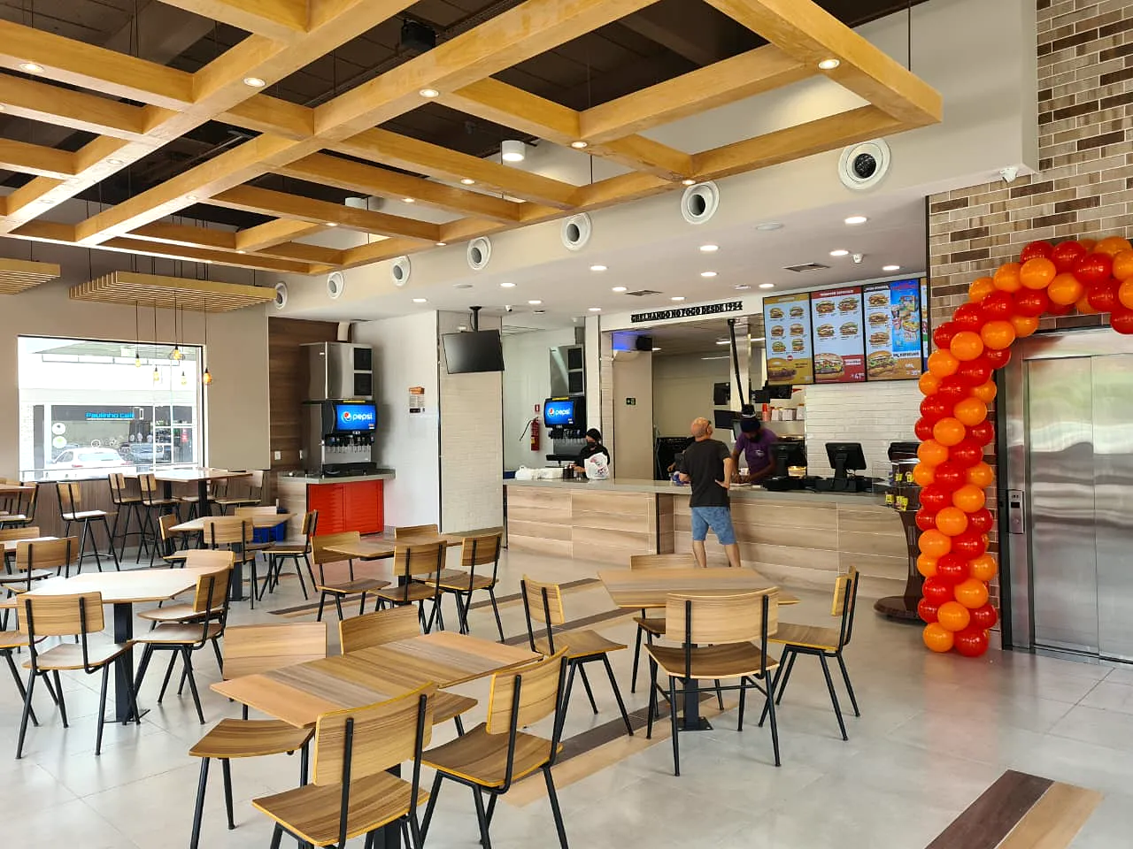 Salão do Burger King da Avenida Djalma Batista, com forro de vigas de madeira, mesas e balcão de atendimento.