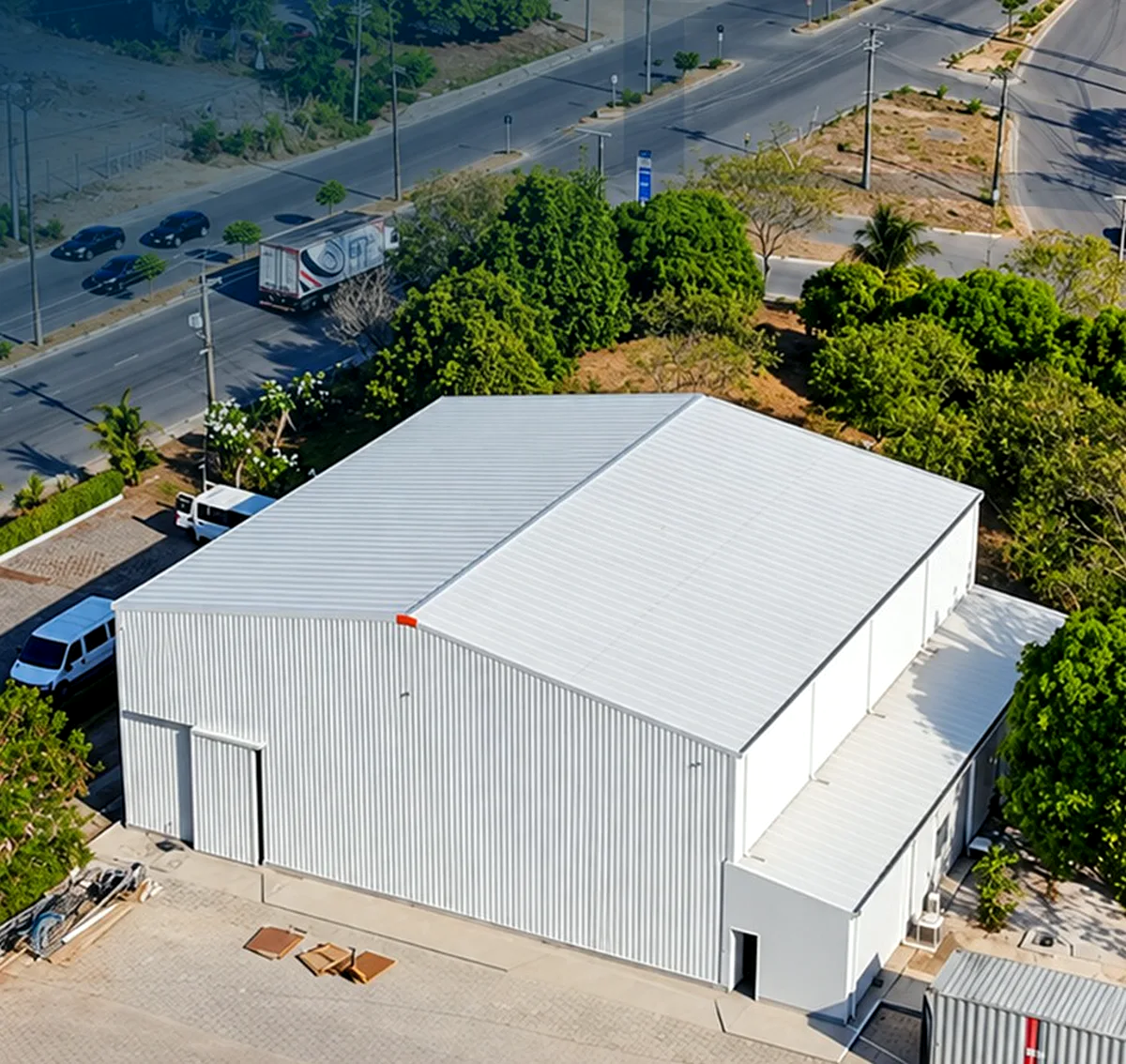 Vista aérea do galpão industrial da Six Label, branco com cobertura metálica, ao lado de avenida.